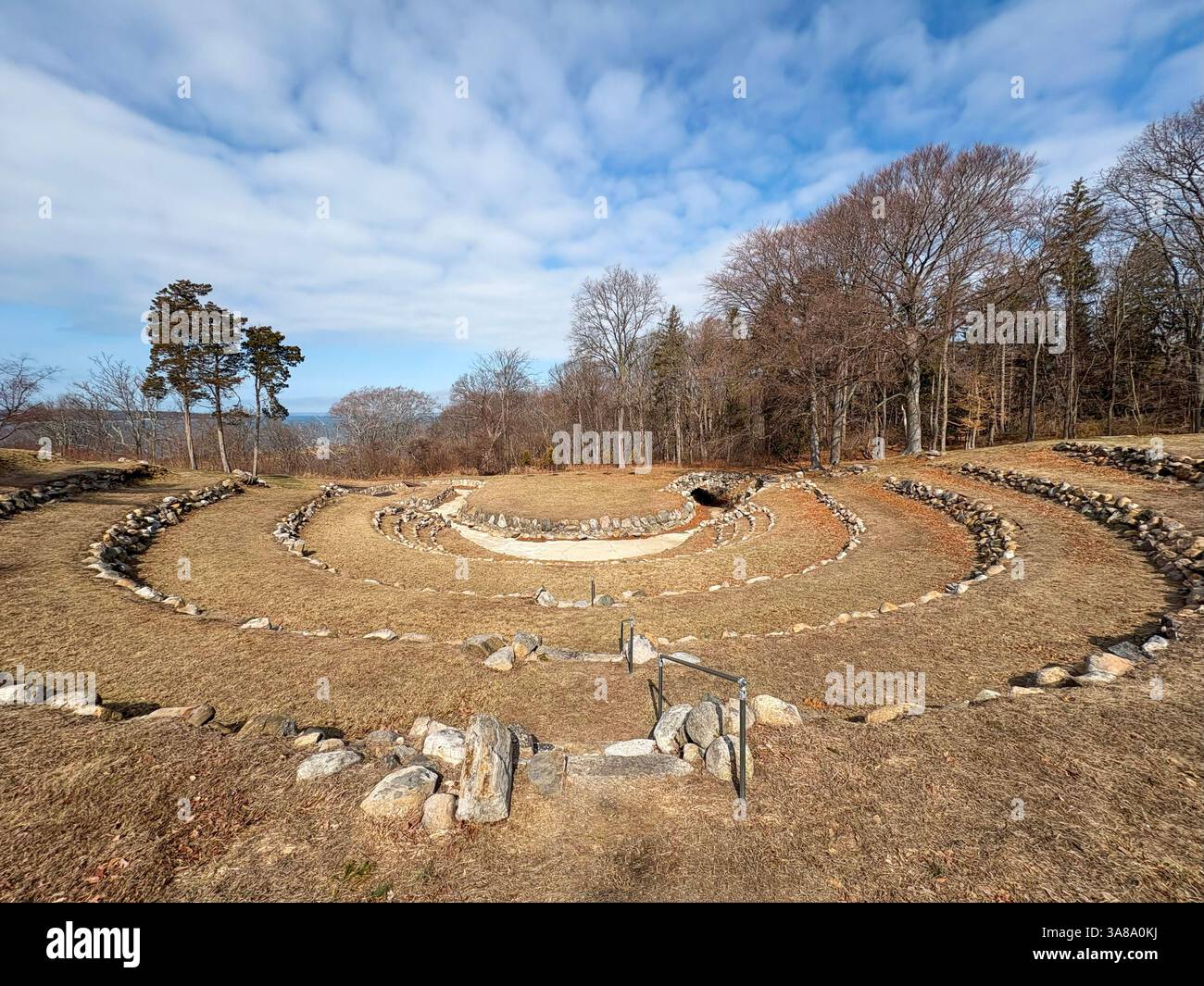 Die antike Steinstruktur befindet sich in einem grasbewachsenen Bereich unter einem Amphitheater mit klarem Himmel. Stockfoto