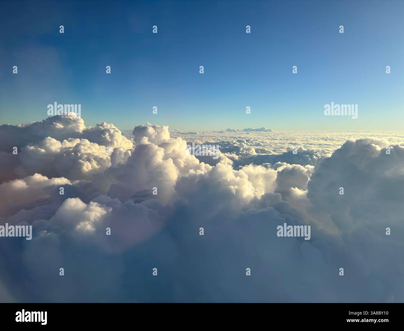 Blick auf flauschige Wolken von oben während eines klaren Himmels bei Sonnenuntergang Stockfoto