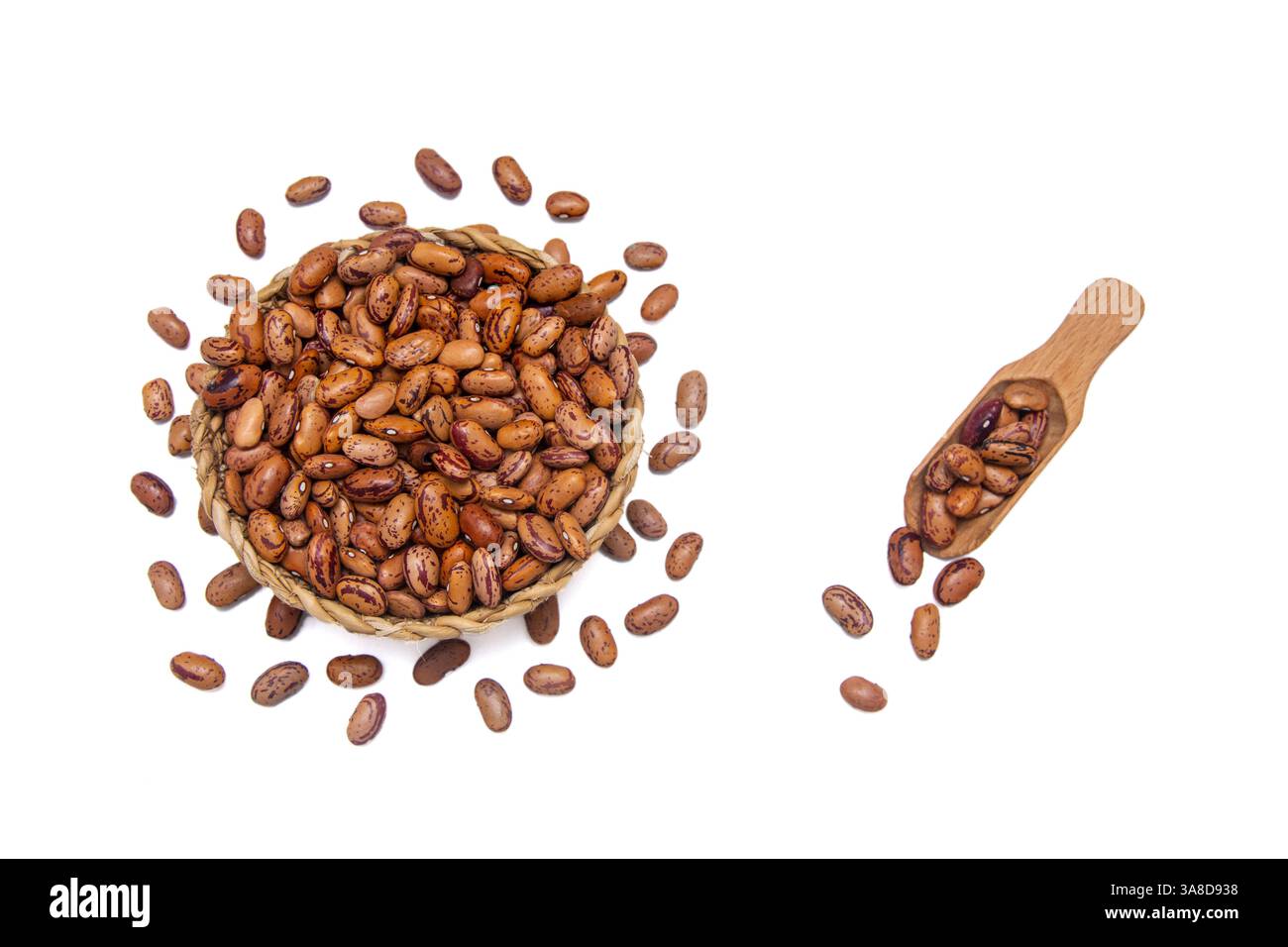 Eine Korbschale gefüllt mit Kidneybohnen, begleitet von einem Holzlöffel, umgeben von Kidneybohnen. Stockfoto