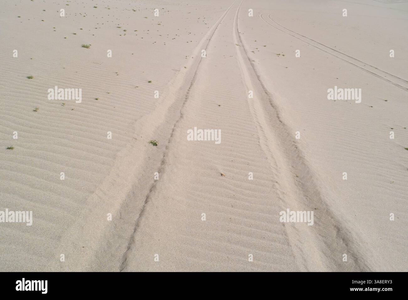 Ein Sandstrand mit ein paar Fußabdrücken im Sand Stockfoto