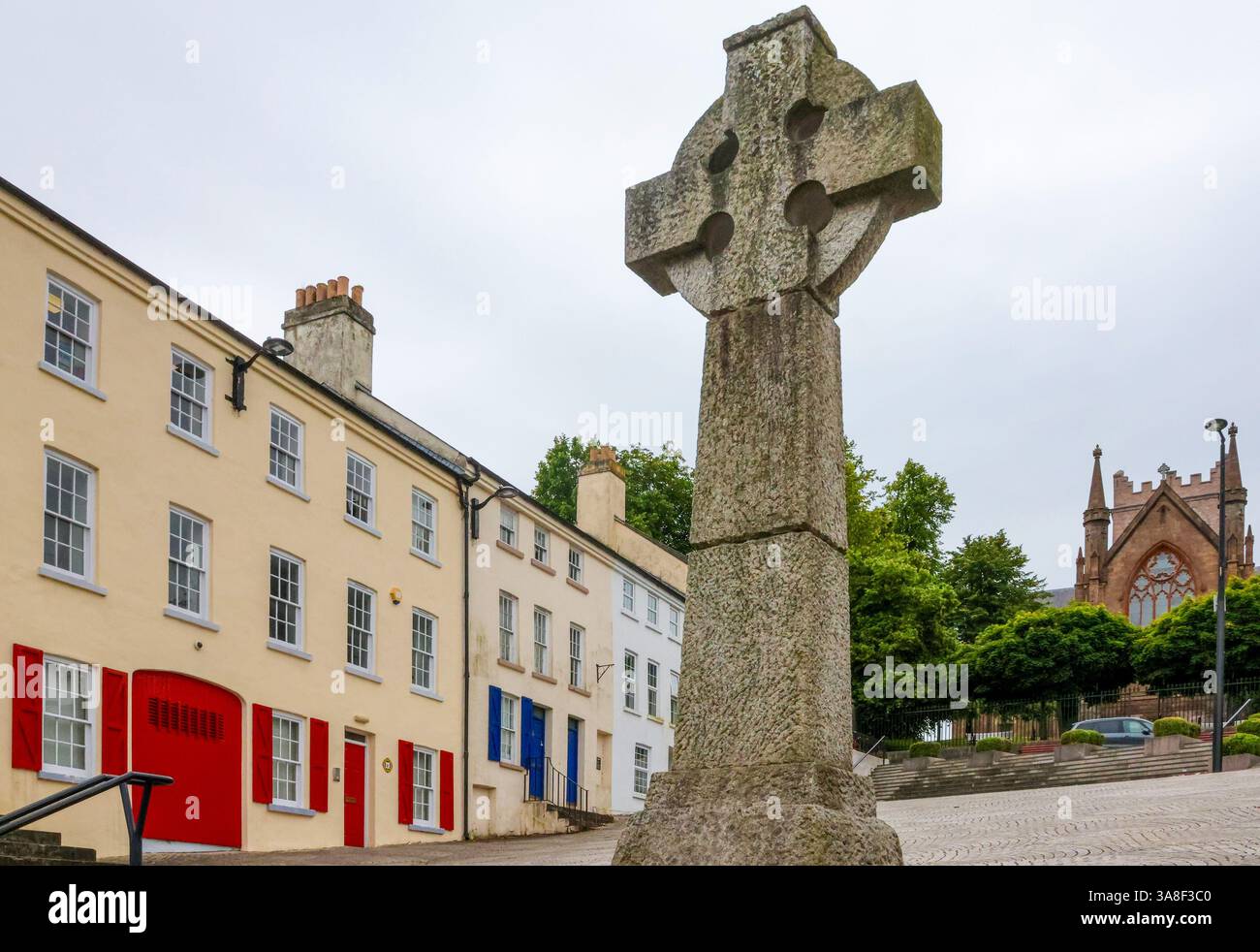 Celtic High Cross Market Square Armagh mit quadratischen Häusern auf der linken Seite und St Patricks Church of Ireland Cathedral im Hintergrund. Stockfoto
