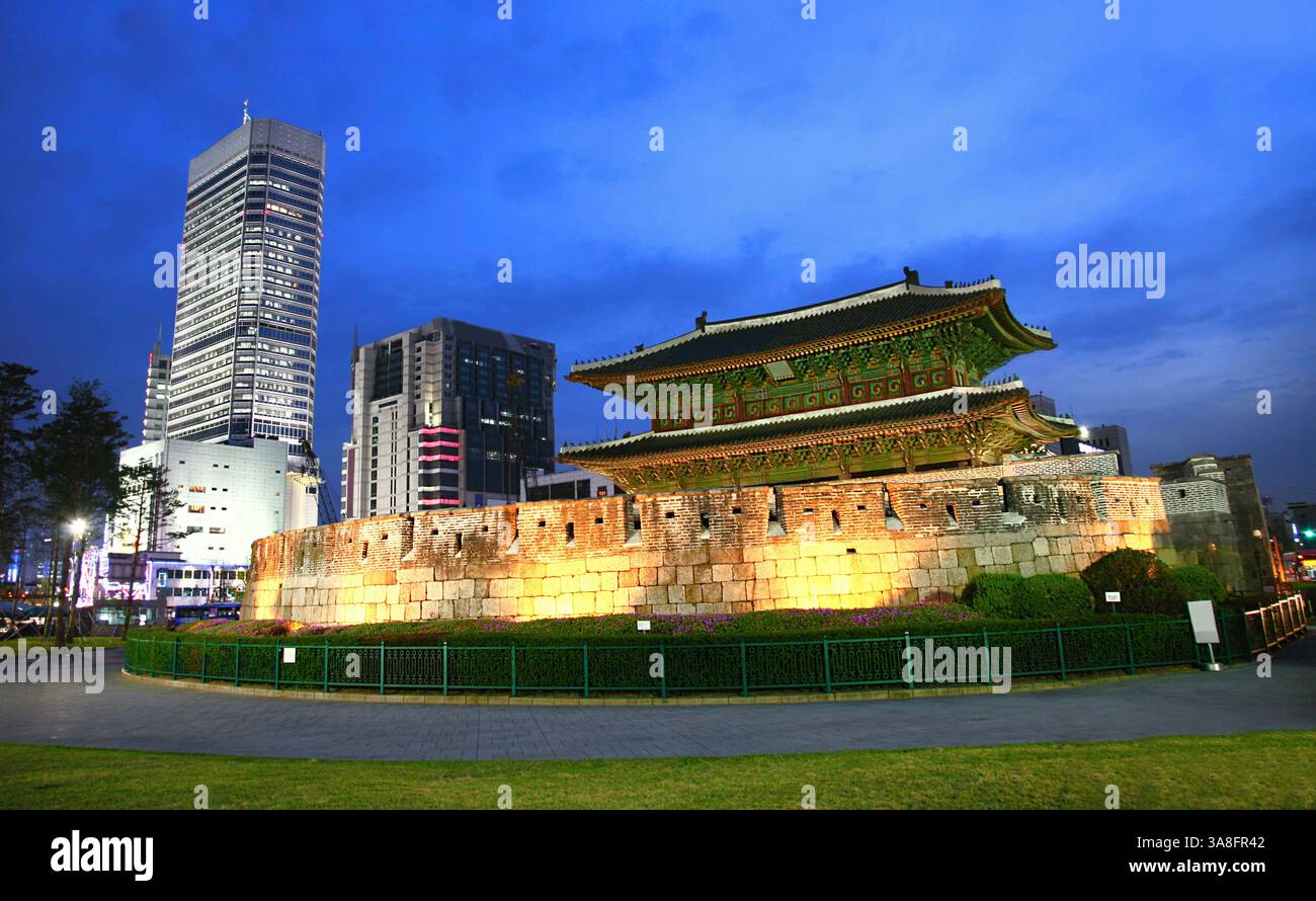 Dongdaemun (Heunginjimun) in Seoul steht bei Nacht beleuchtet und kontrastiert traditionelle koreanische Architektur mit der modernen Skyline der Stadt. Stockfoto