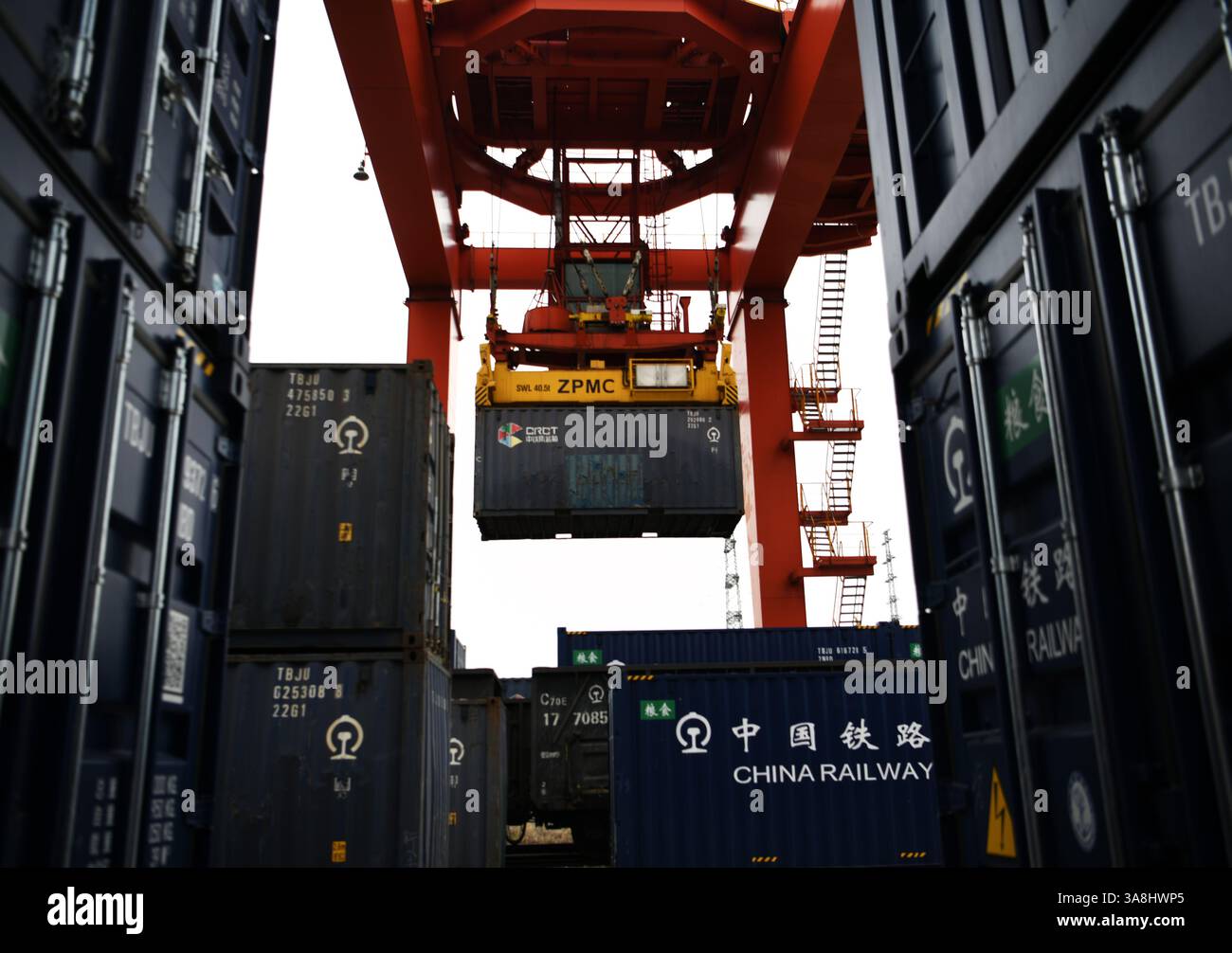 Ein Portalkran hebt Getreidebehälter in einen Zugwagen auf der speziellen Eisenbahnlinie des Hafens Jiujiang Chengxi in Jiujiang, Provinz Jiangxi, China weiter Stockfoto