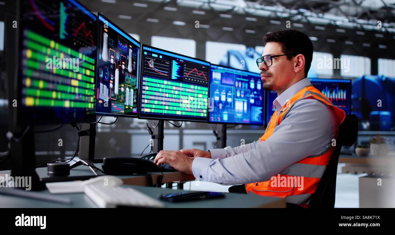 Latino Engineer überwacht das SCADA-System der Ölraffinerie auf dem Desktop. Stockfoto