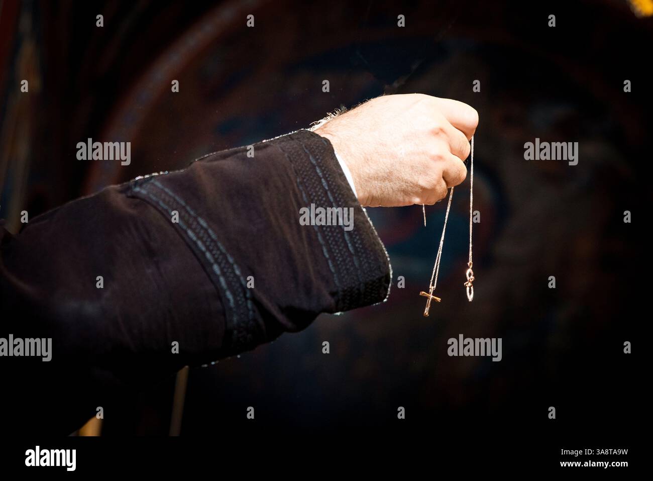 Ein Priester mit zwei Kreuzen während einer griechischen orthodoxen Taufe. Stockfoto
