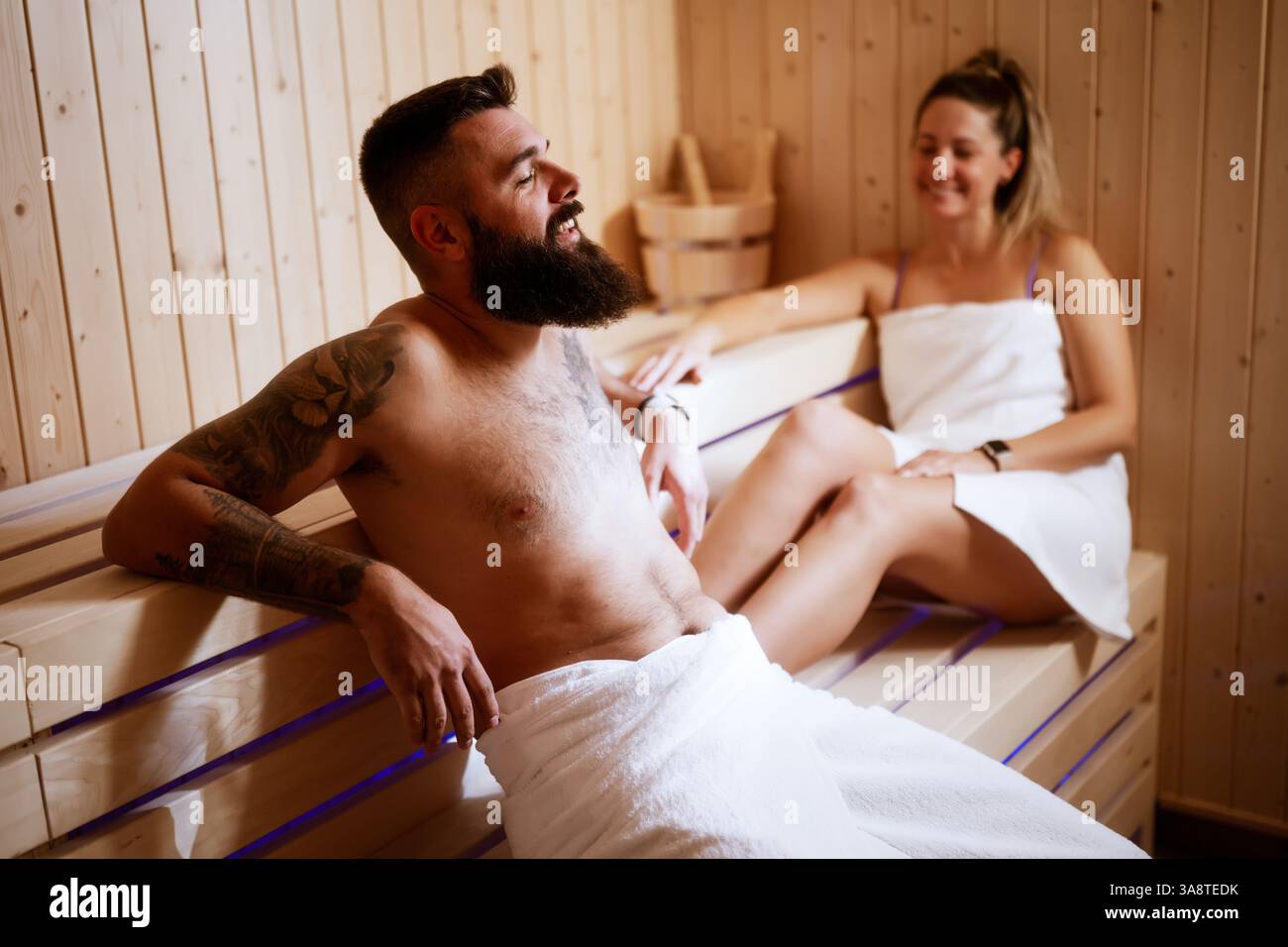 In weiche Handtücher gehüllt, genießt ein Paar eine private Sauna in einem gehobenen Spa. Stockfoto