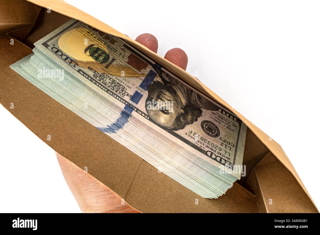 Verborgenes Glück: Eine Hand hält zärtlich einen offenen Umschlag voller knackiger Hundert-Dollar-Scheine, die Wohlstand und finanzielle Freiheit repräsentieren. Stockfoto