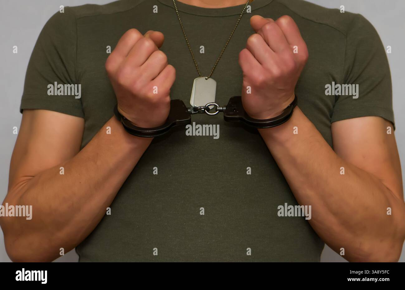 Ein Militär hat Handschellen mit einem Soldatenmedaillon um den Hals. Konzept: Verbrechen in der Armee, Festnahme und Bestrafung von Militärpersonal, Entsendung Stockfoto