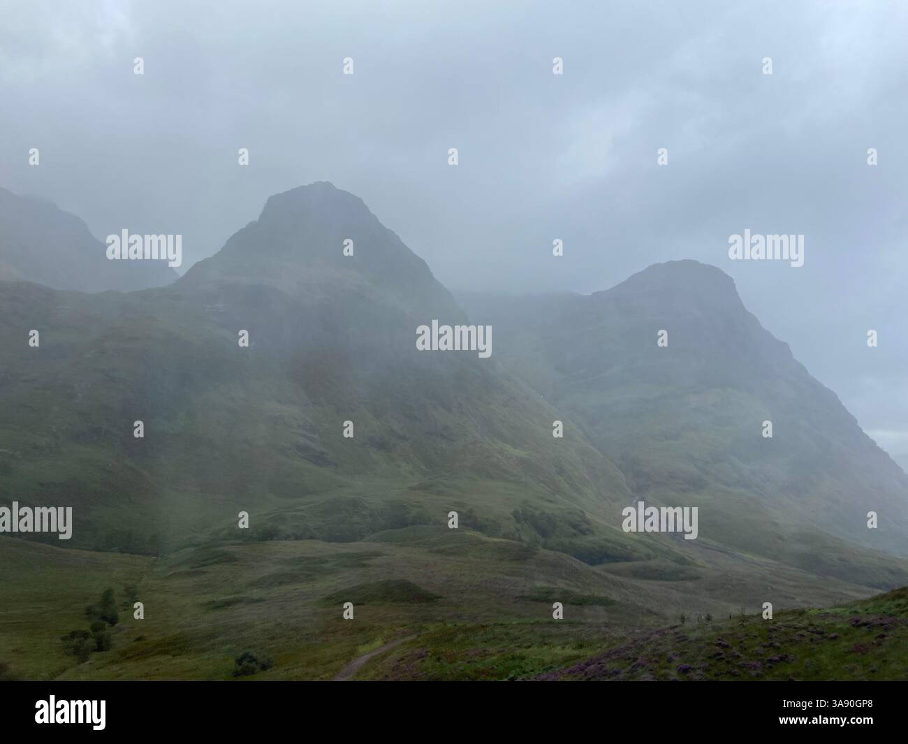 Die nebelige Unheimlichkeit der schottischen Highlands, die durch die Berge sickern. - Smartphone-aufgenommenes Stockfoto