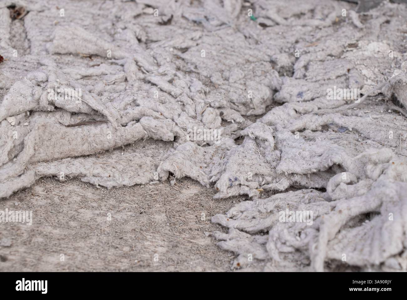 Alte zerrissene Baumwollwolle auf einem Stuhl unter der Polsterung als Hintergrund, zerrissener schmutziger Stoff, zerrissener Lappen Stockfoto