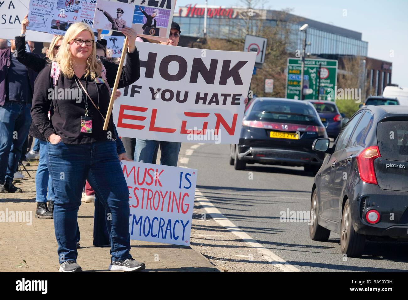 März 2025, London, Großbritannien. Demonstranten gegen Elon Musk und seine politischen Aktionen bei der US-Kundgebung vor dem Tesla Car Showroom im Park Royal, London. Der Londoner Protest ist Teil eines globalen Aktionstages unter dem Dach der Tesla Takedown-Bewegung. Die Organisatoren sagen, dass die Kundgebungen vor mehr als 200 Tesla-Standorten weltweit stattfinden werden. Die Demonstranten ermutigen die Autofahrer, beim Besuch des Tesla Showrooms in London die Hupe zu läuten. Stockfoto