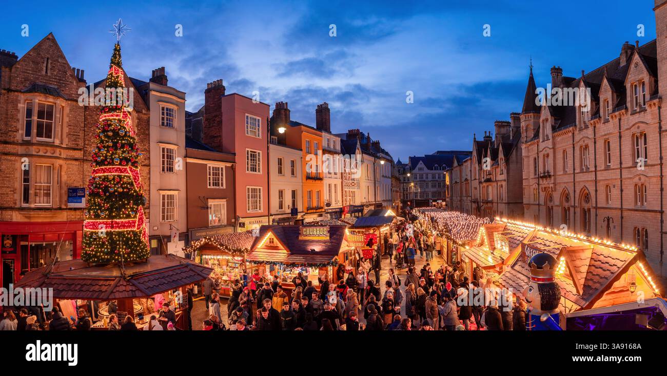 Oxford, England, Großbritannien - Ein festliches Weihnachtsmarkt mit leuchtenden Ständen, einem riesigen, verzierten Baum und historischer Architektur bei Nacht Stockfoto