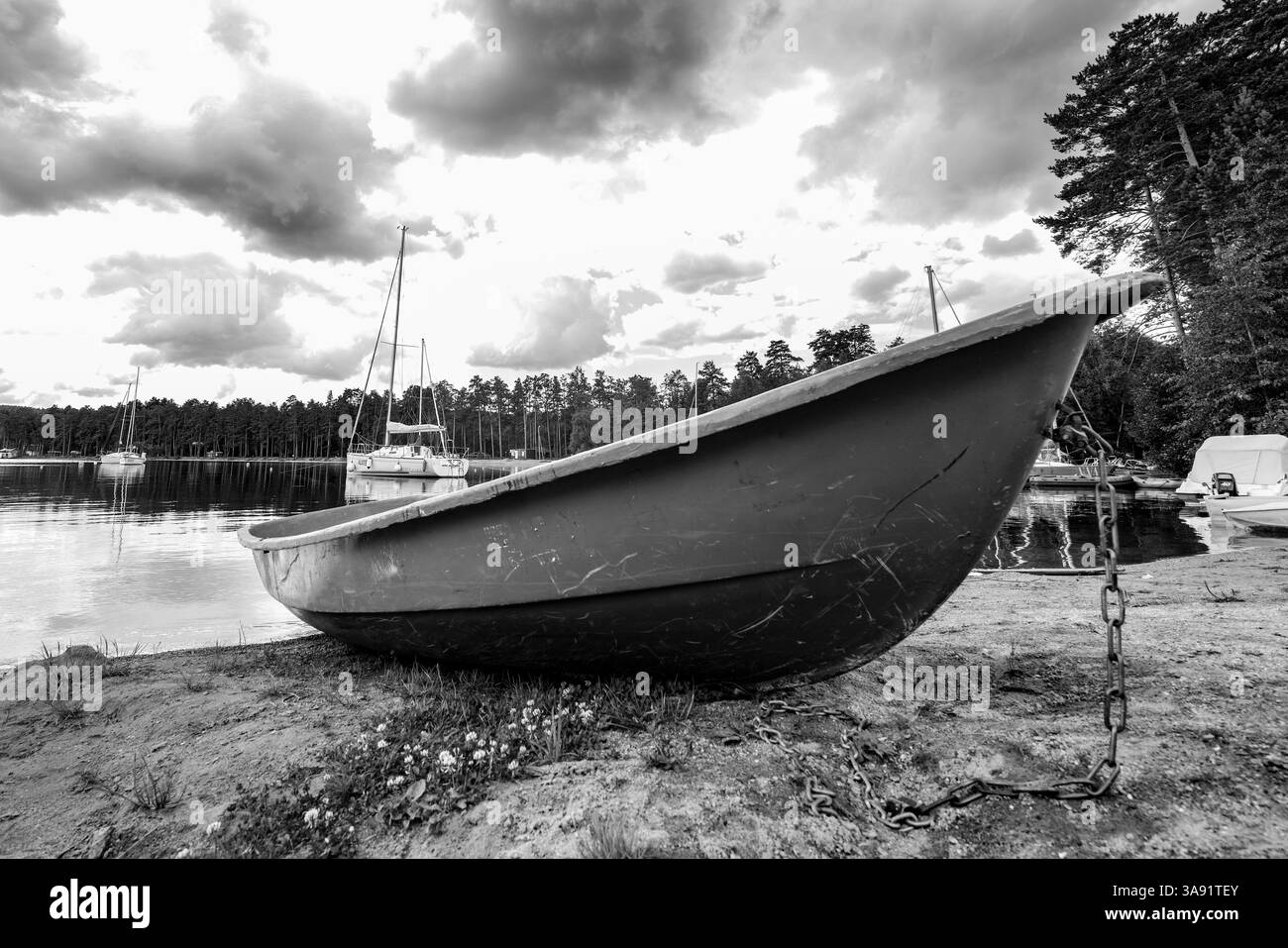 Ein kleines Boot sitzt auf dem Sand in der Nähe des Wassers. Das Boot ist an eine Kette gebunden Stockfoto