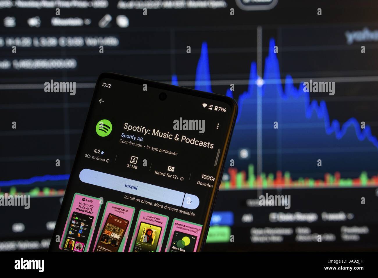 Der Installationsbildschirm der Spotify Music App auf einem Smartphone und die Finanzmarktkarte im Hintergrund Stockfoto
