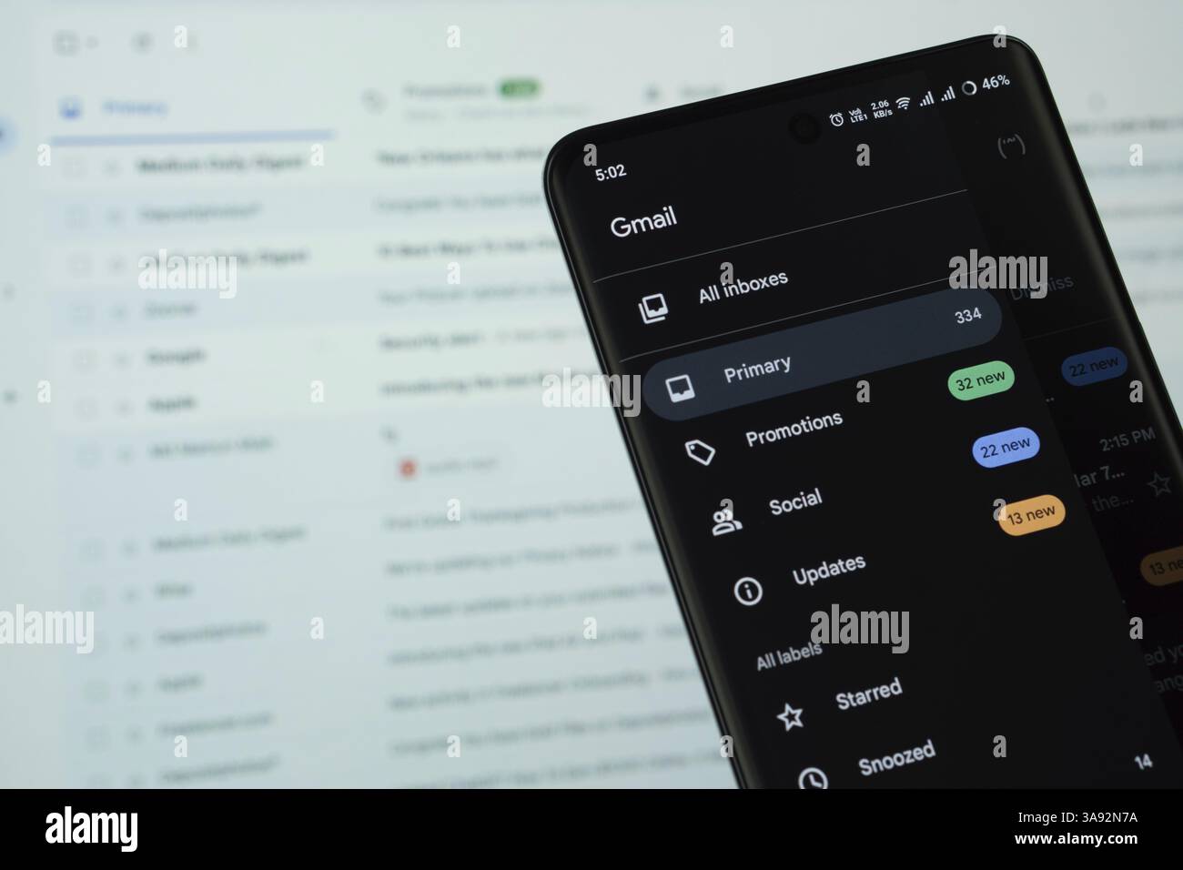 Das Logo der Gmail wird auf einem Smartphone-Bildschirm angezeigt, und die Website-Gmail wird auf einem Computerbildschirm im Hintergrund angezeigt Stockfoto