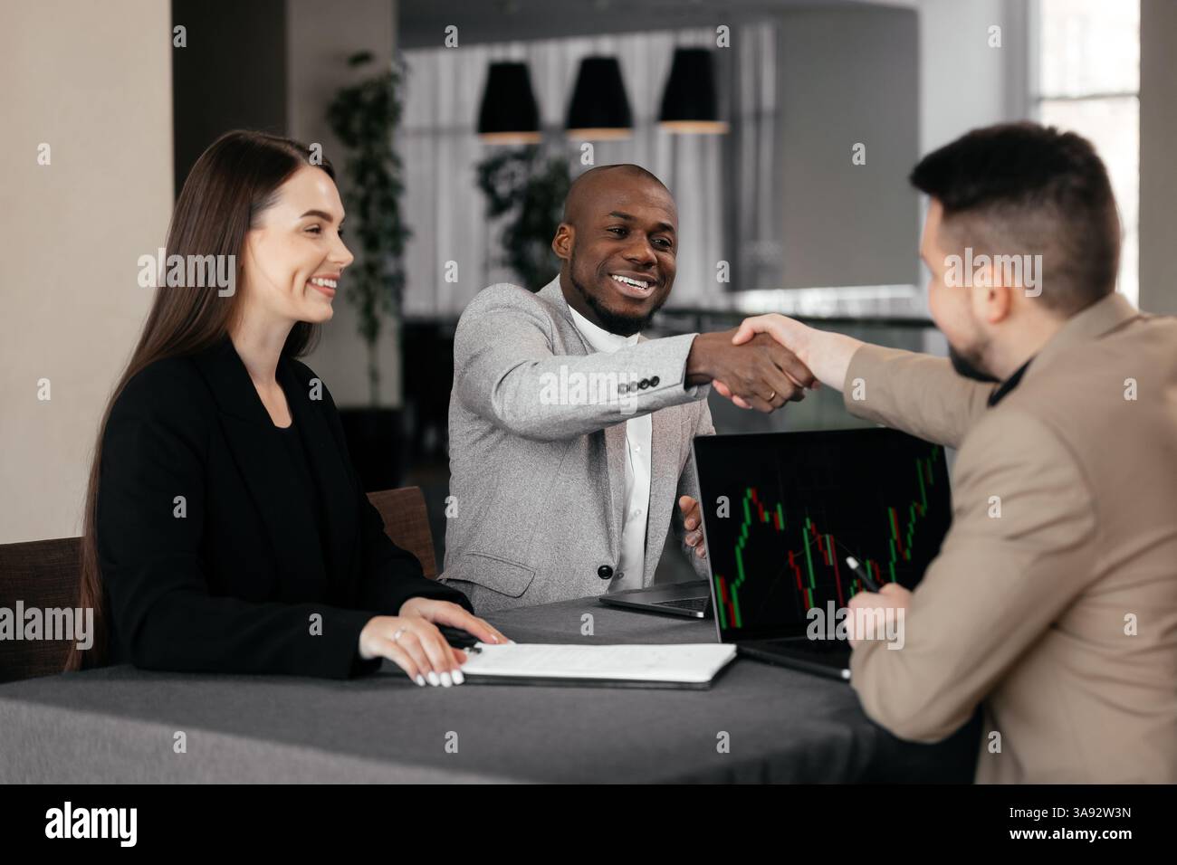 Lächelnder afrikanischer Finanzberater, Anwalt oder Bankmanager, der männlichen Klienten-Investor berät und Dokumente bei Geschäftstreffen liest Stockfoto