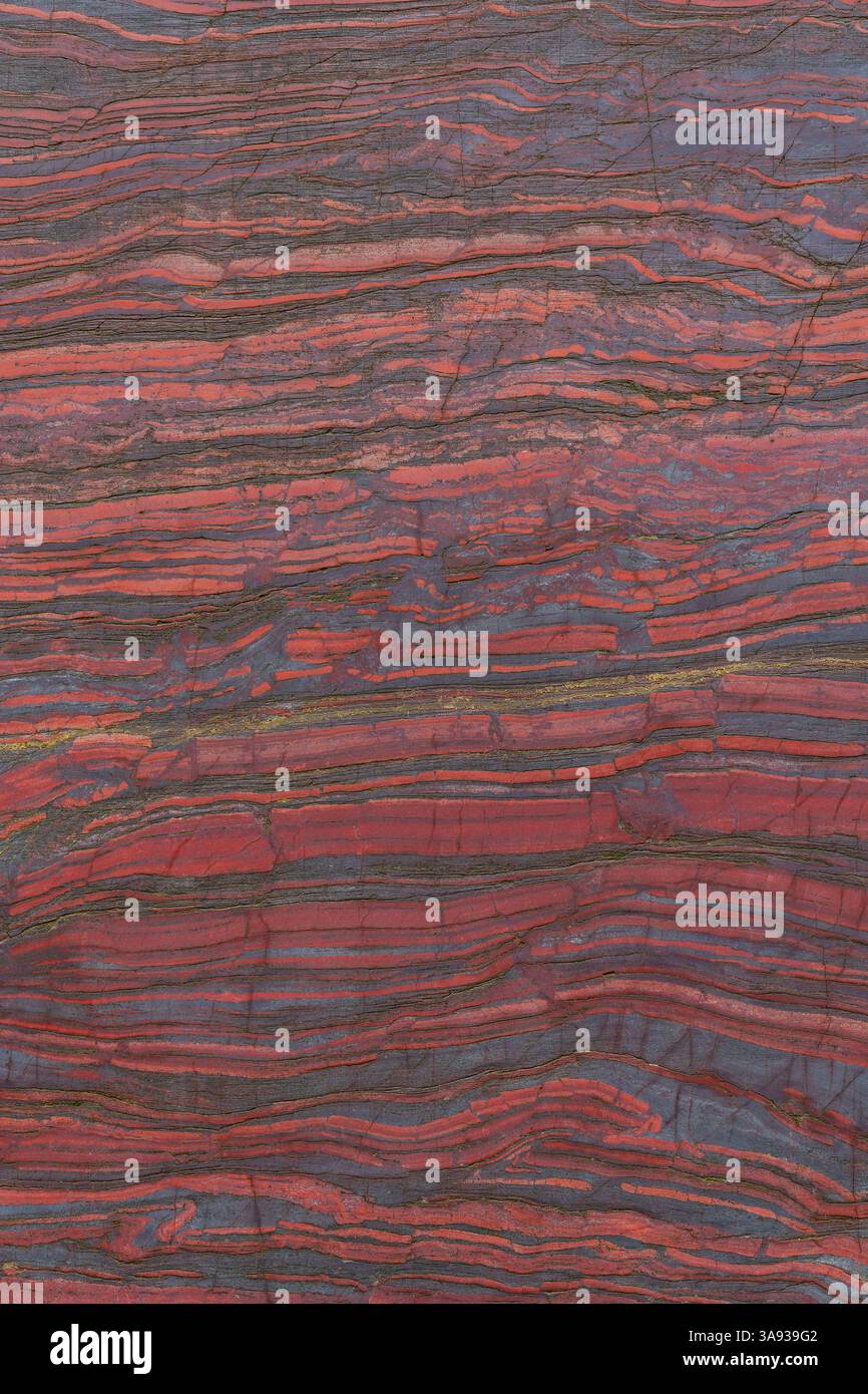 Nahaufnahme geschnittener roter Stein mit natürlichen Mustern und Texturen. Bändereisenerz. Mineralstruktur, geologische Schichten, natürlicher Hintergrund für die Gestaltung. Stockfoto