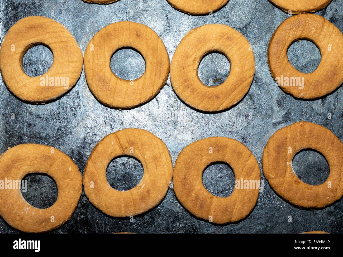 Donut-Formen aus angereichertem Teig sitzen auf einem Blech und bereiten das Frittieren vor. Die kreisförmigen Formen heben die Konsistenz des Teigs vor dem Kochen hervor Stockfoto