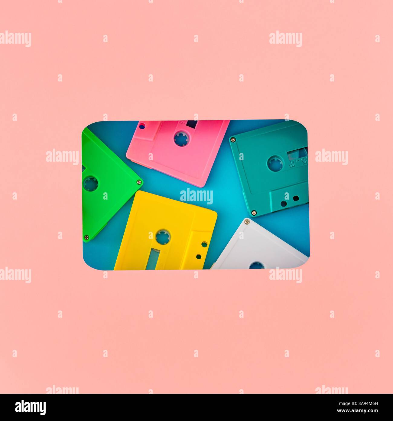 Layout im Vintage-Stil mit bunten alten Audiokassettenkassetten, sichtbar durch eine kassettenförmige Lücke auf blauem Hintergrund. Stockfoto