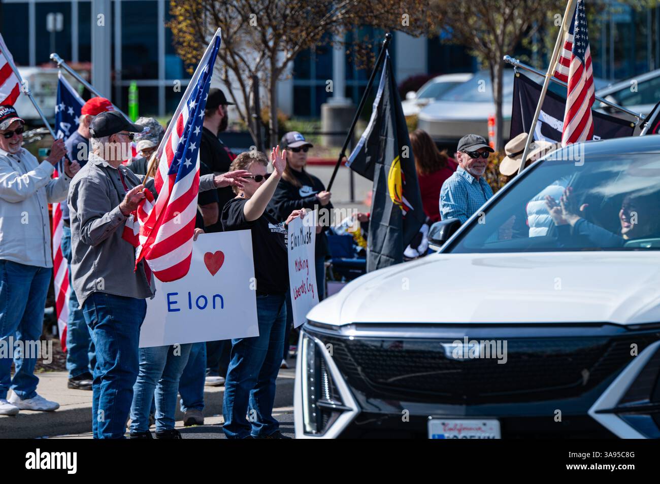 Ein Unterstützer winkt Elon Musk-Unterstützern außerhalb des Tesla-Händlerbetriebs während eines „Takeback“-Protestes zu. Die Demonstranten von Tesla Takedown waren auf der anderen Straßenseite. Stockfoto