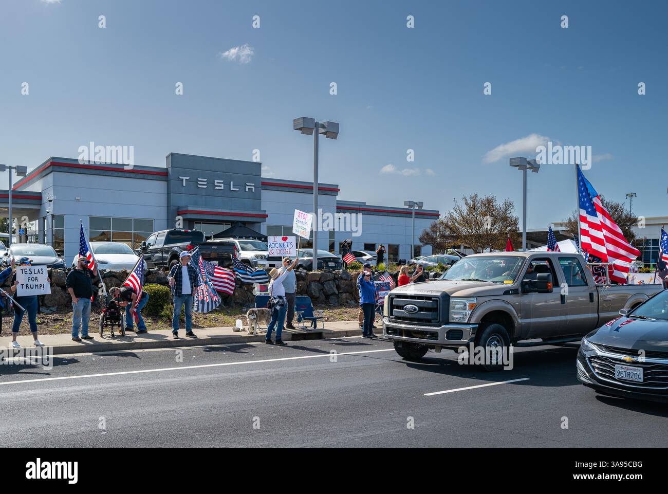 Trump/Tesla-Unterstützer widersprechen dem Protest in einem Tesla-Händlerbetrieb nach den Protesten gegen Elon Musk und DOGE. Die Demonstranten waren auf der anderen Straßenseite Stockfoto