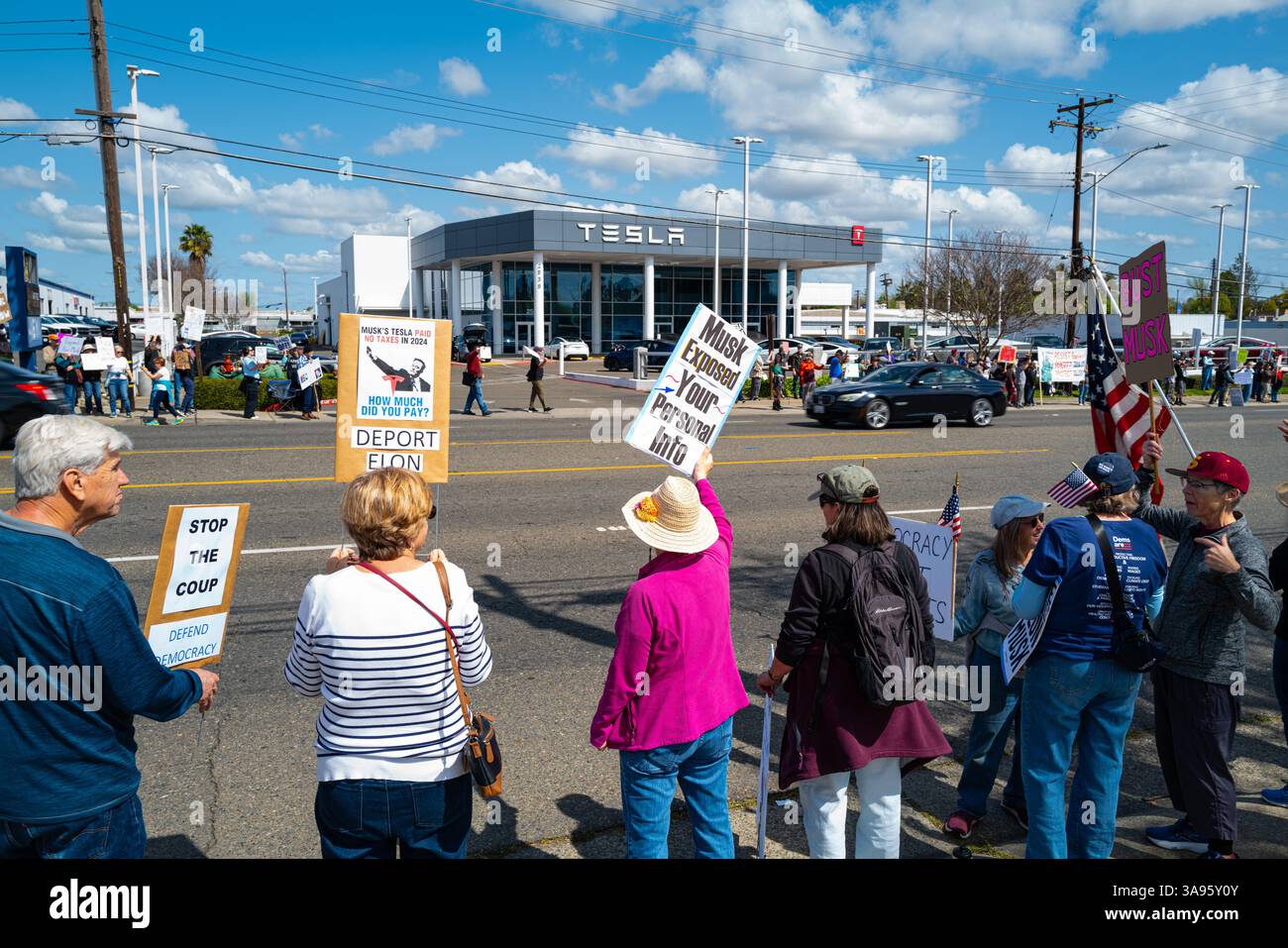 Eine Frau hält einen Musk in der Hand, der Ihr Personal in der Nähe des Arden Way Tesla Händlers bei einem Protest gegen den CEO des Unternehmens und seine DOGENARBEIT enthüllt hat. Stockfoto