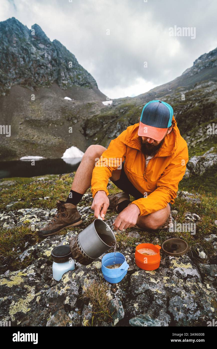 Mann kocht Camping Essen im Freien mit Gasherd Ausrüstung auf Picknick in Bergen Backcountry Küche - Reise allein Wandern Überlebensausflug Abenteuer Urlaub Stockfoto