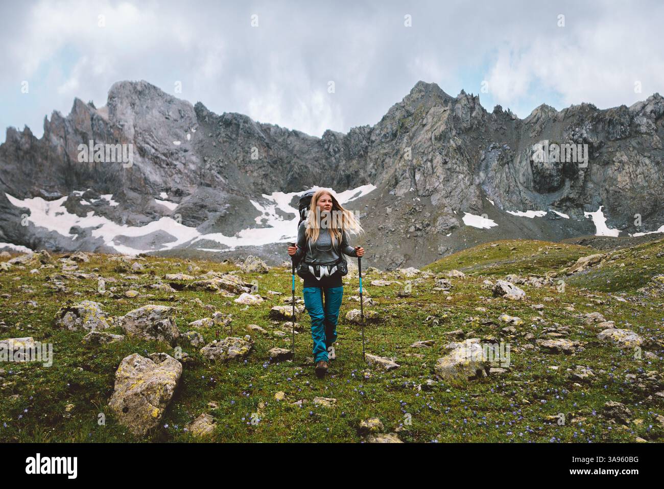 Frau klettert Berge mit Trekkingstöcken und Rucksackausrüstung Reise Abenteuer Lifestyle Wandern Alleinreisender auf wilden Naturpfaden, ac Stockfoto