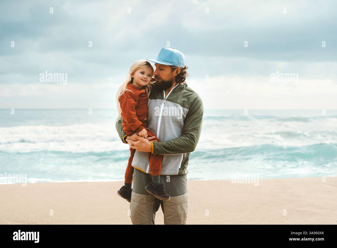 Vater und Tochter spazieren am Strand, umarmen und genießen glückliche Familienmomente, offene Emotionen - Elternschaft Liebe miteinander. Unterwegs im Freien Stockfoto