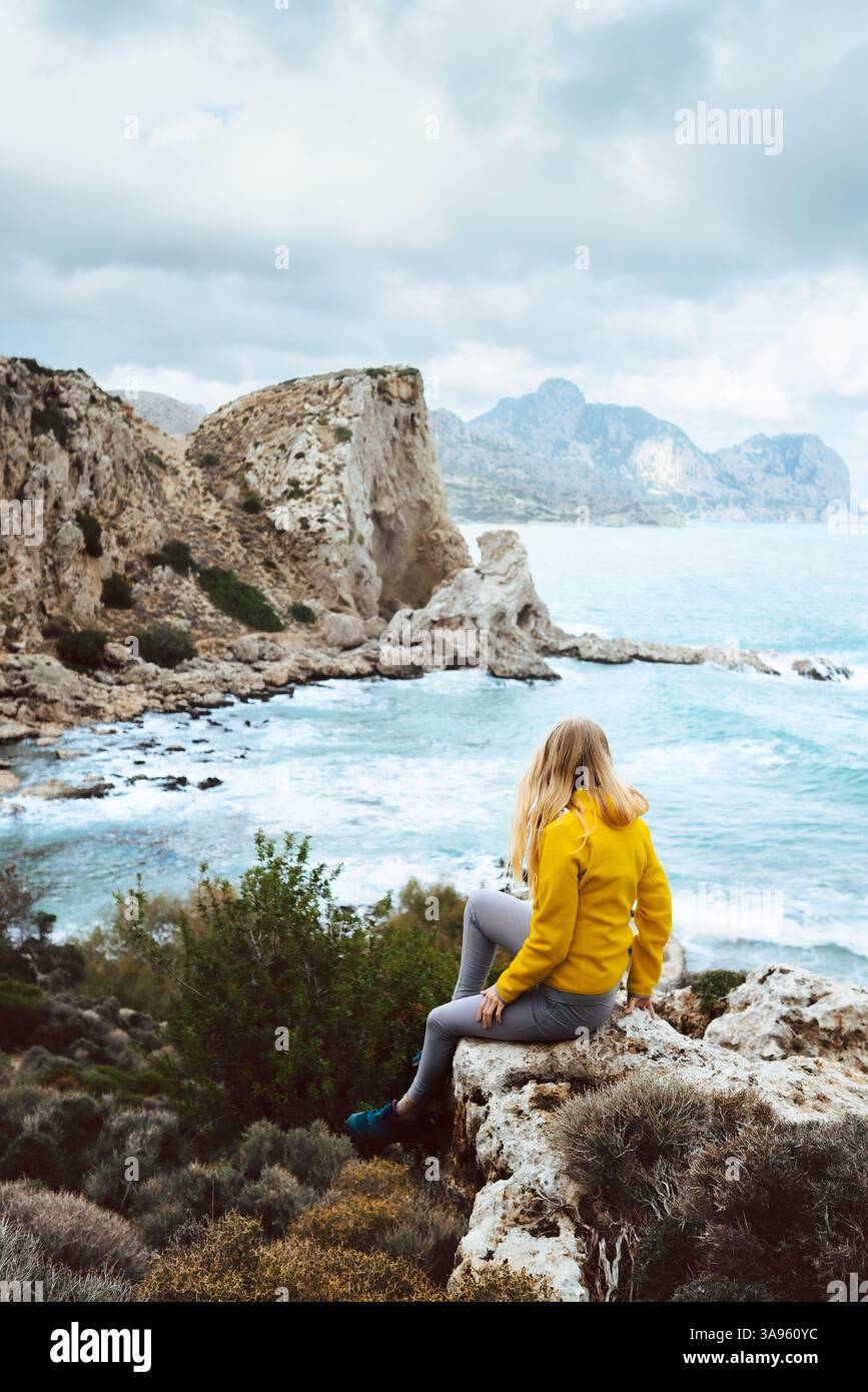 Frau, die in Griechenland allein durch die Sehenswürdigkeiten der Natur reist, aktive Ferien Wandern im Freien, Touristenmädchen genießt Felsen und Meerblick auf Rhodos isla Stockfoto