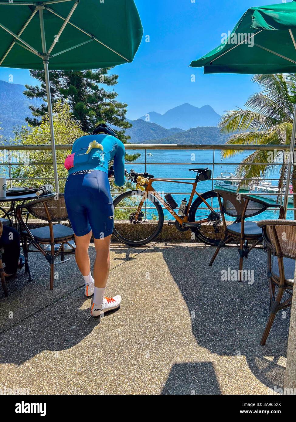 Yuchi, Taiwan, Sun Moon Lake, Man, Radfahrer, Sportkleidung von hinten, Fotos von seinem Fahrrad auf der Starbucks Cafe Terrace Stockfoto