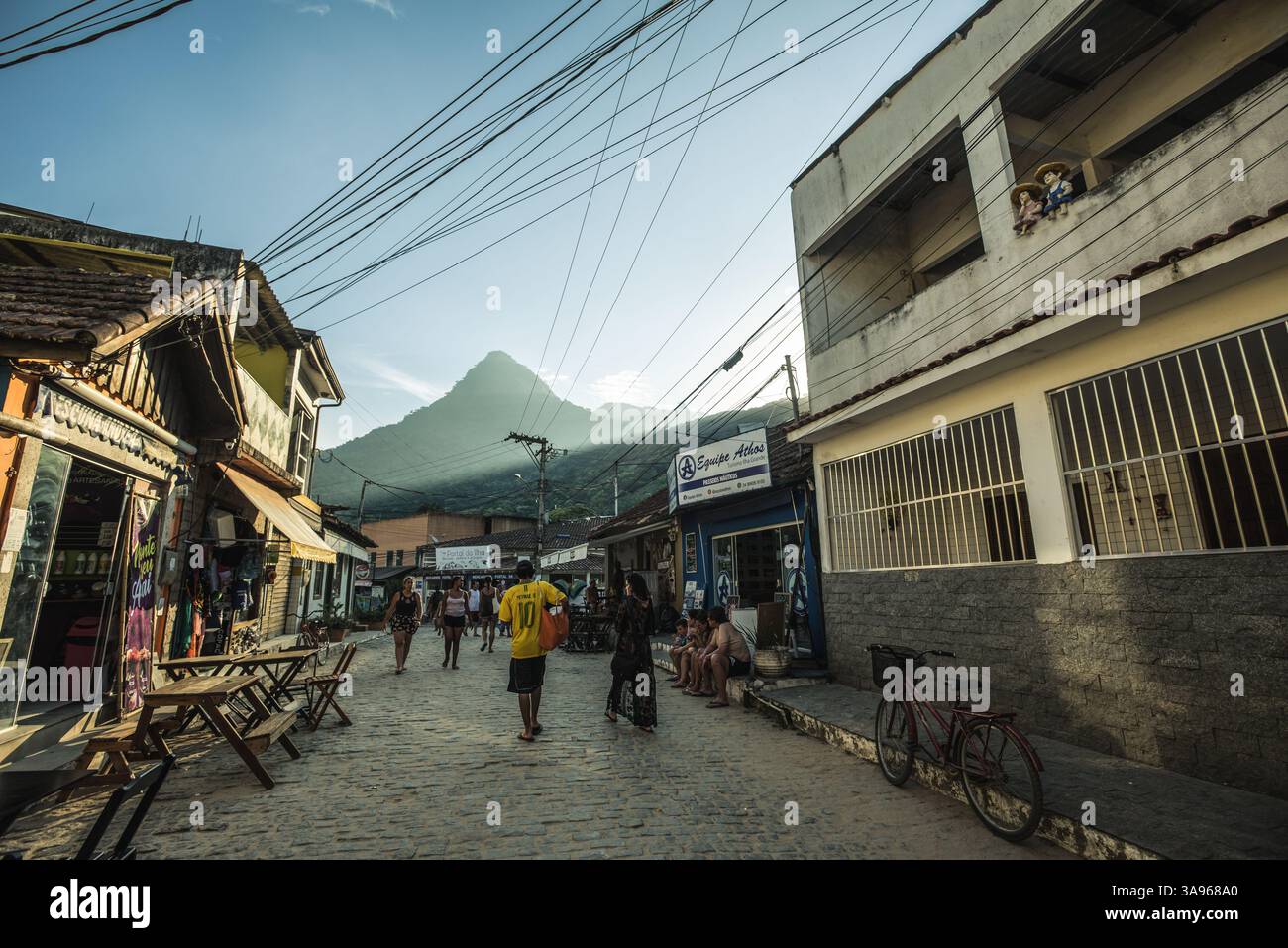 Menschen gehen durch eine Kopfsteinpflasterstraße in Vila do Abraão – Ilha Grande, Brasilien Stockfoto