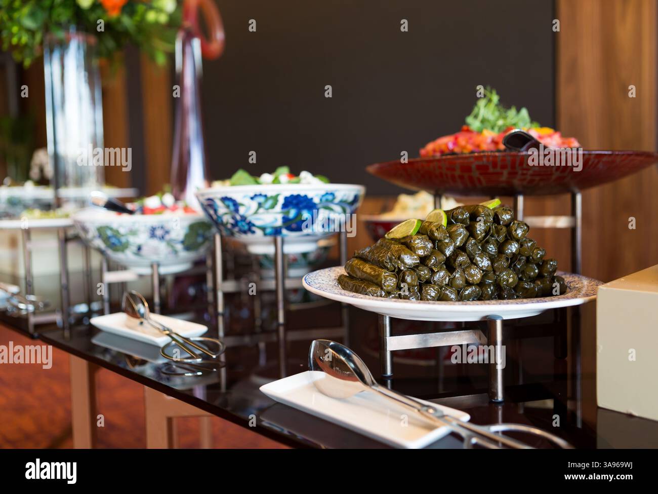 Ein wunderschön gestalteter langer Tisch mit einer reichen Auswahl an türkischer Küche, eingerichtet für ein festliches Bankett oder eine festliche Feier, geschmückt mit eleganten Blumen Stockfoto