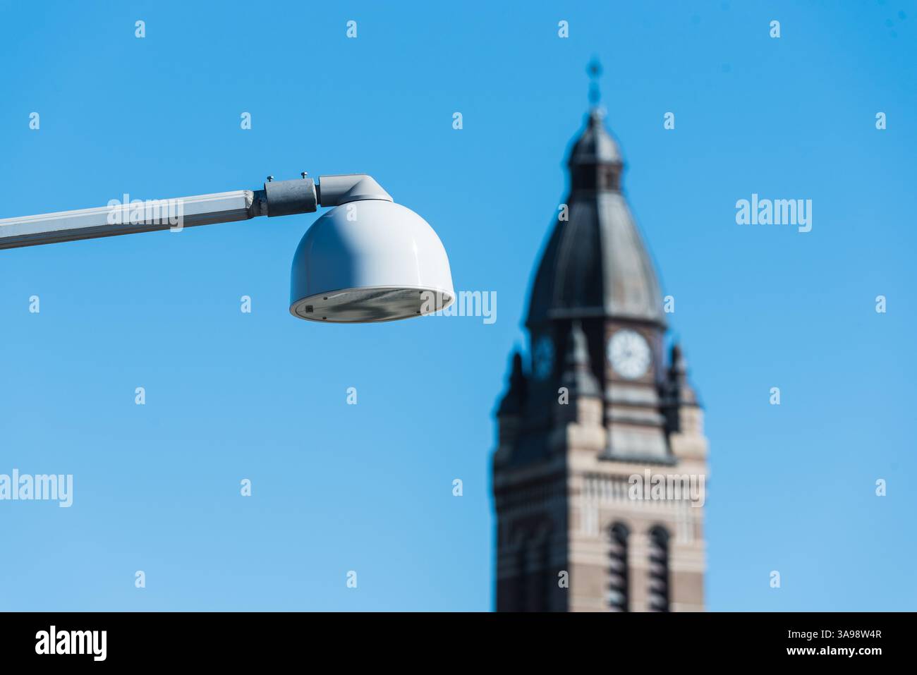 Eine Straßenlaterne steht gut sichtbar vor einem historischen Kirchturm in Göteborg. Die Uhr auf dem Turm trägt zum Charme bei und fängt die ess ein Stockfoto