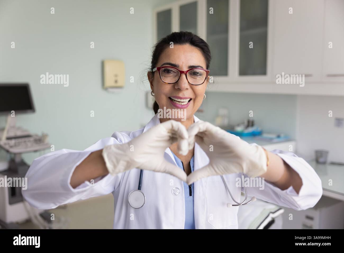 Glückliche Kardiologin, die Finger in Herzform verbindet Stockfoto