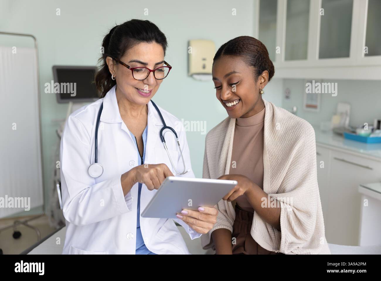 Fröhlicher junger Schwarzer Patient und reife Ärztin mit Tablette Stockfoto
