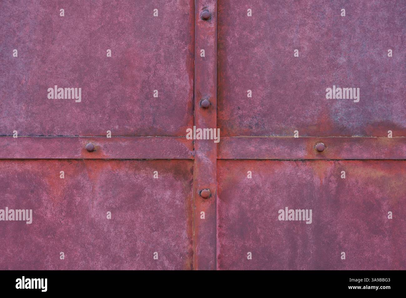 Detaillierte Ansicht der verwitterten roten Metalltafel mit Distress Markierungen, Texturen und genieteter Konstruktion. Spiegelt industriellen Charme und rustikale Themen wider. Stockfoto