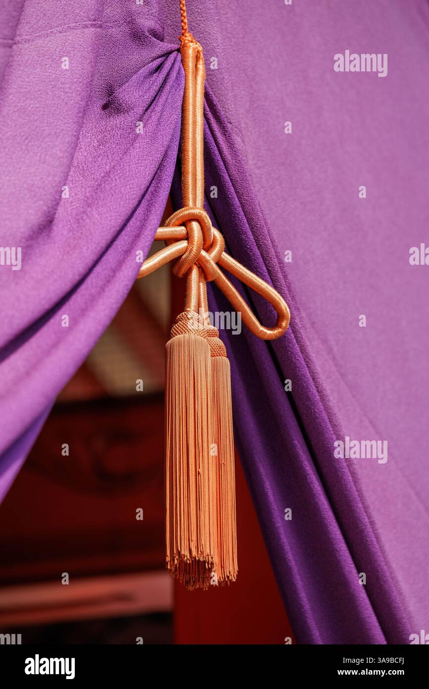 Eleganter goldener Quastenrücken schmückt den Eingang zum hondo des japanischen buddhistischen Tempels, oder der wichtigsten Buddha-Halle, die mit einem üppigen lila Vorhang verziert ist. Stockfoto