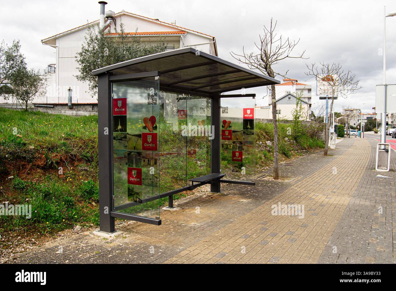 Fatima, Portugal - 24. März 2025: Öffentliche Bushaltestelle mit Glaspaneelen in einem Wohngebiet in Fatima, Portugal, umgeben von Grün. Stockfoto