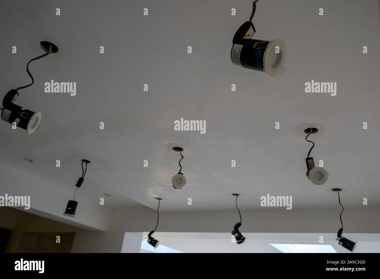 Die Abbildung zeigt eine Decke unter Arbeit mit mehreren Einbaustrahlern, die neu installiert werden Stockfoto