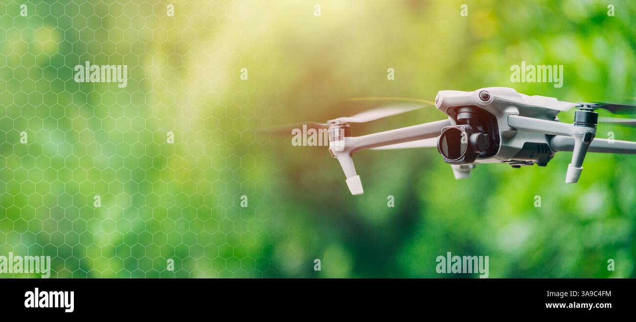 Drohnen-UAV unbemanntes Luftfahrzeug mit Kamera, Drohne fliegt auf unscharfem grünem Hintergrund breites Banner mit Kopierraum für Text. Stockfoto