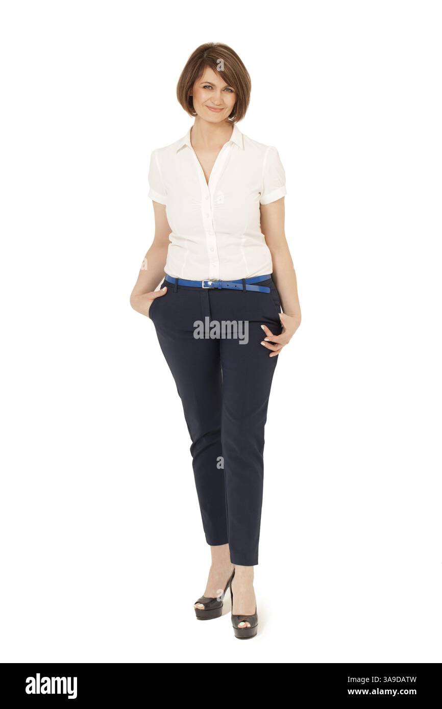Lächelnde Erwachsene Frau mit kurzen Haaren und eleganter Bluse, Hose und High Heels vor weißem Hintergrund. Studio-Aufnahme, isoliert Stockfoto