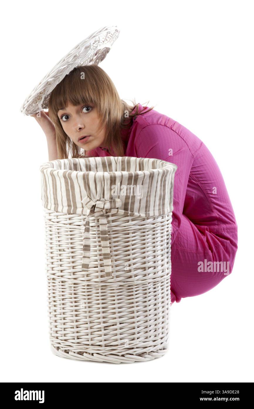 Schönes Mädchen, das sich für einen Korb für Leinen verstecken kann Stockfoto