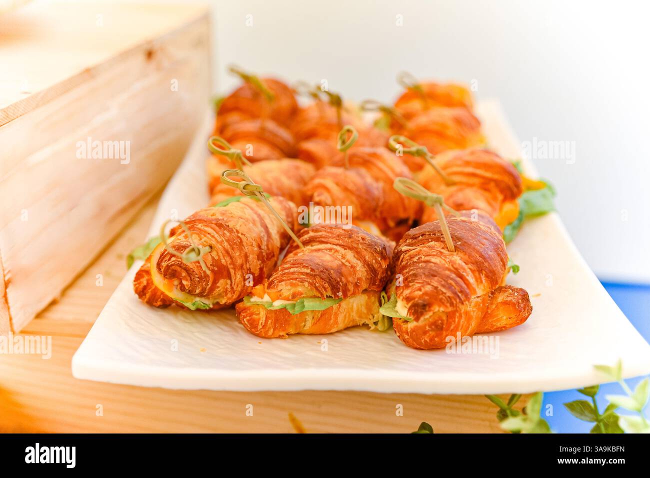Nahaufnahme köstlicher Mini-Croissant-Sandwiches mit Salat und Käse, ordentlich arrangiert für ein Buffet oder Catering-Event. Stockfoto
