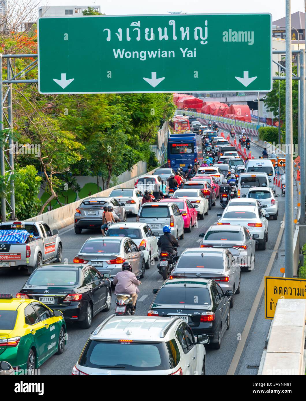 Thailand-15 Mai 2024: Warteschlangen mit viel Verkehr am Nachmittag bewegen sich langsam unter dem umweltfreundlichen erhöhten Weg, gefüllt mit Pflanzen, Blumen, Grün Stockfoto