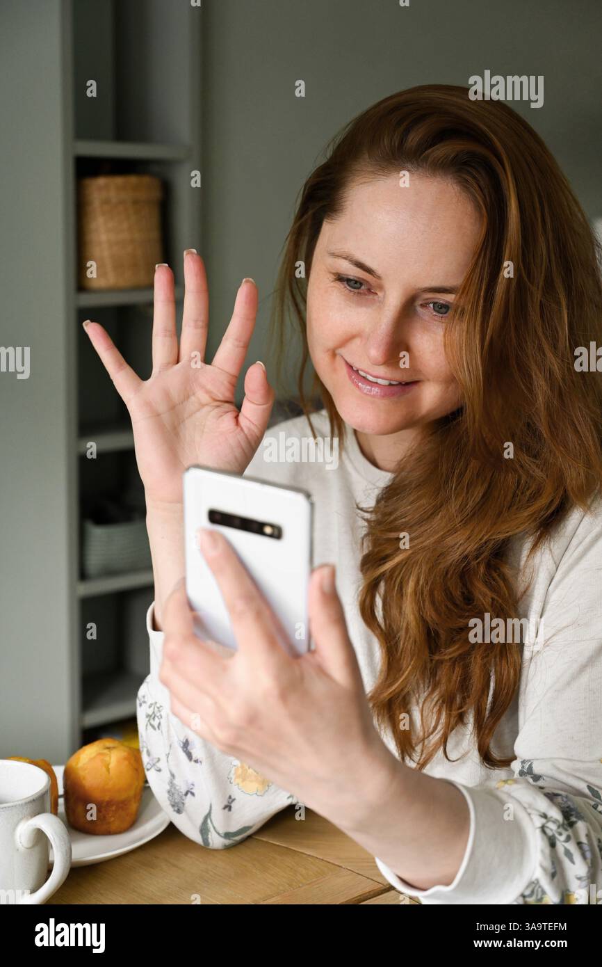 Frau, die auf den Smartphone-Bildschirm schaut, Videoanruf von zu Hause aus Stockfoto