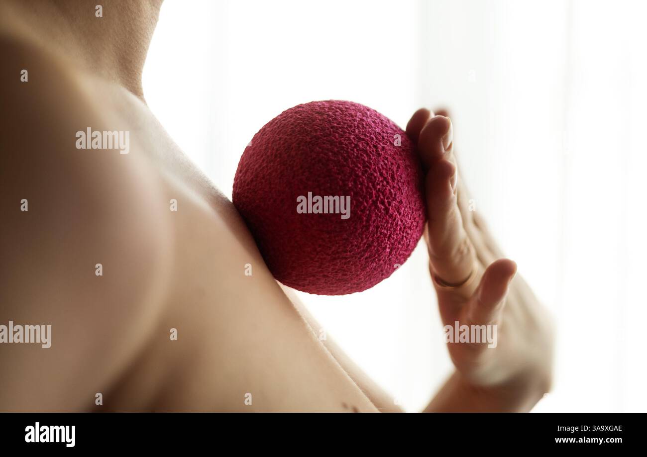Nahaufnahme einer Frau, die Massageball auf den Rippen mit der Hand rollte Stockfoto