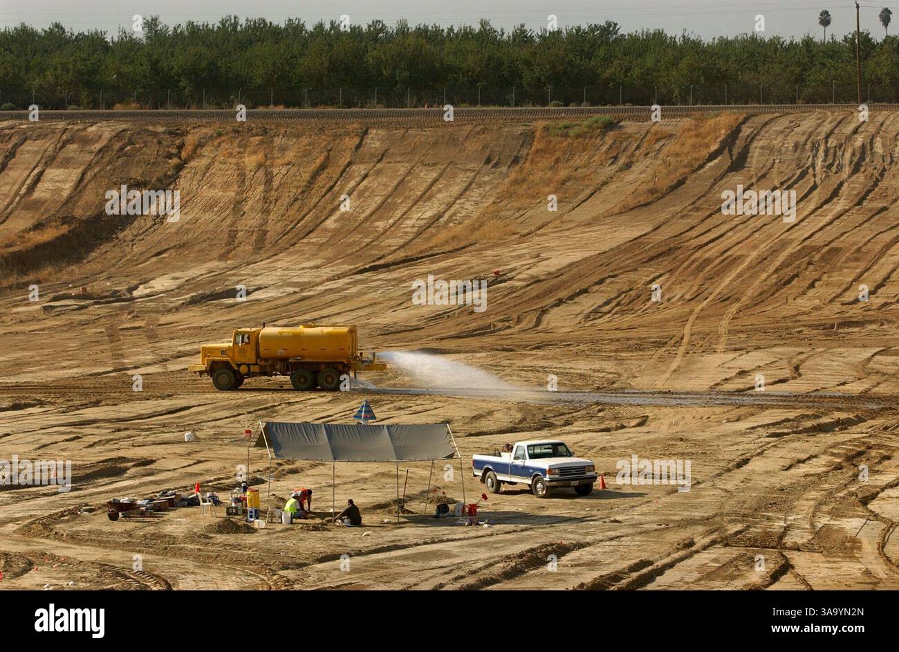 SEKUNDÄR- Paläontologen arbeiten daran, Knochen im Schatten einer Plane aufzudecken, während ein Wasserwagen den Staub in einer Zelle auf der Madera-Deponie in Chowchilla am 3. September 2003 hält. Paläontologen haben Knochen von 36 prähistorischen Tierarten gefunden, darunter riesige Faultiere, Mammuts und sabertooth-Tiger, die vor etwa 12 Jahrtausenden in Kalifornien umherstreiften. Wissenschaftler nennen es die größte Fossilienfunde aus dem Pleistozän, die jemals an der Westküste gefunden wurde. Die Sacramento Bee / Randy Pench / ZUMA Press Stockfoto