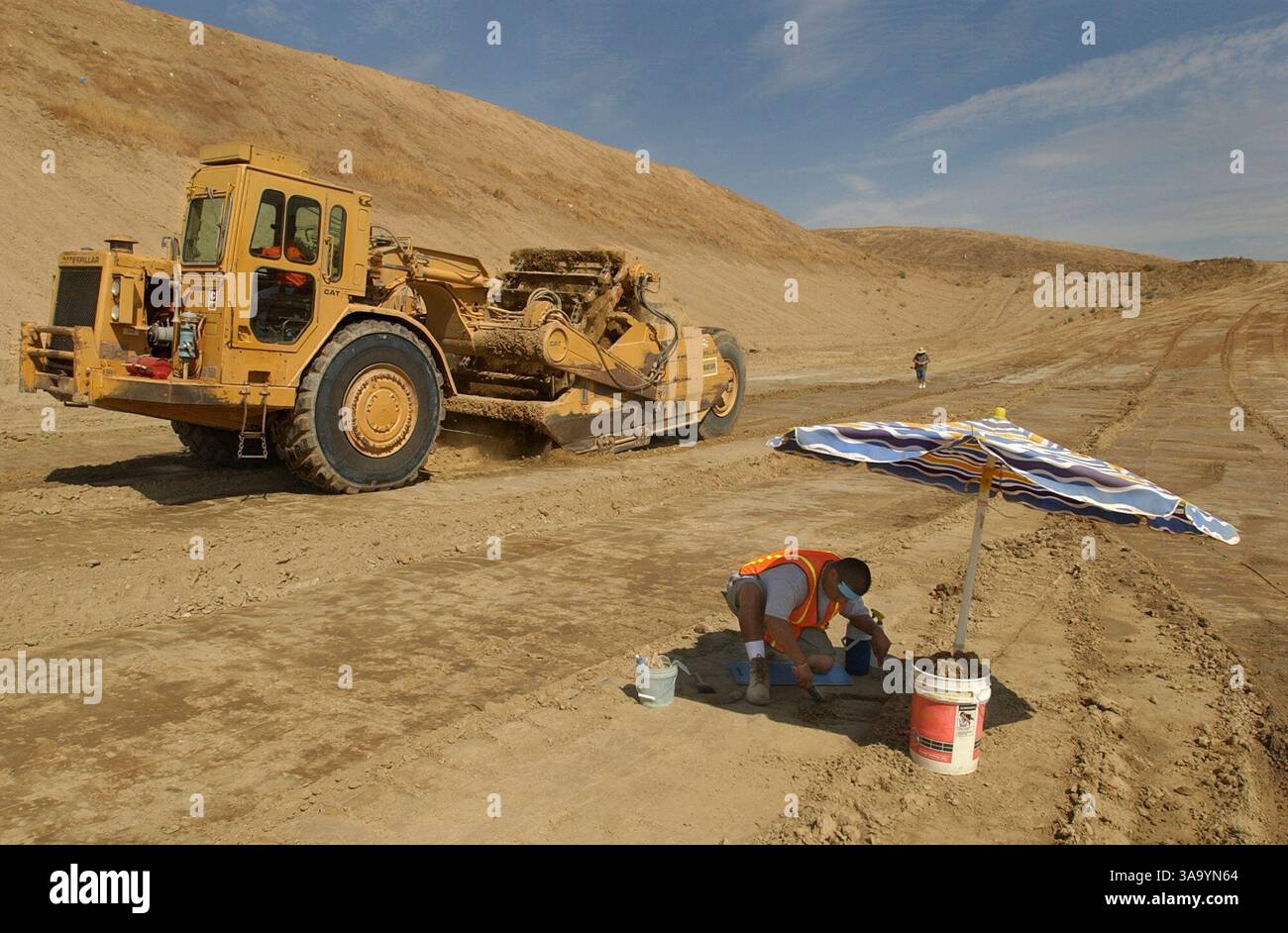 JUMP-- Alfonso Contreras (cq) überprüft eine mögliche Knochenentdeckung, während er am Mittwoch, 3. September 2003 im Schatten eines Regenschirms auf der Madera-Deponie in Chowchilla arbeitet. Ein Abstreifer entfernt Schmutz, der zu den möglichen Entdeckungen führt. Paläontologen haben Knochen von 36 prähistorischen Tierarten gefunden, darunter riesige Faultiere, Mammuts und sabertooth-Tiger, die vor etwa 12 Jahrtausenden in Kalifornien umherstreiften. Wissenschaftler nennen es die größte Fossilienfunde aus dem Pleistozän, die jemals an der Westküste gefunden wurde. Die Sacramento Bee / Randy Pench / ZUMA Press Stockfoto