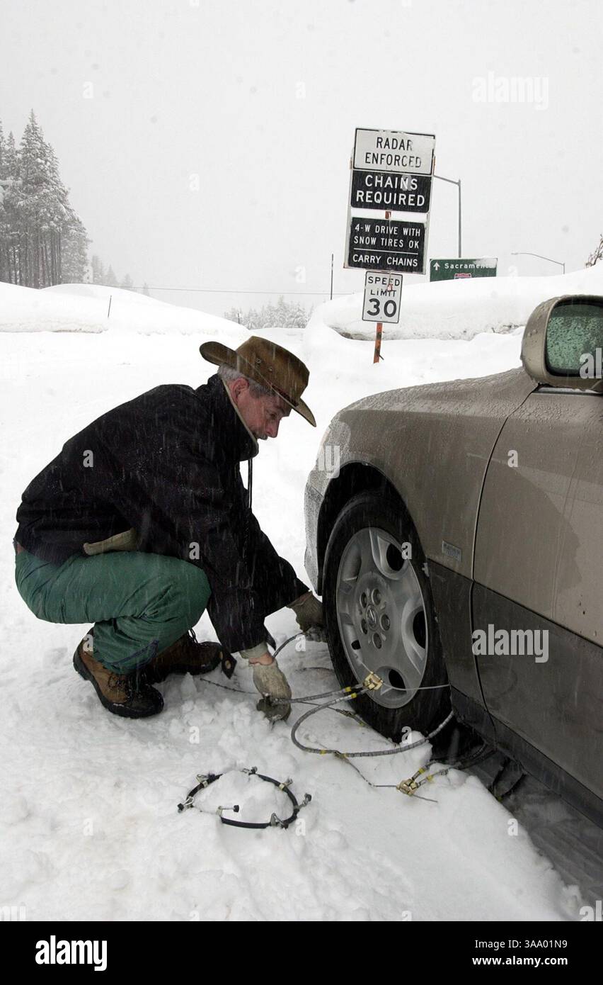 Richard Ross aus Sacramento arbeitet an der Reparatur seiner gebrochenen Schneeketten am Soda-Spring-Ableger der I80 während des Wintersturms, der am Mittwoch, den 25. Februar 2004 durch Nordkalifornien zog. Sacramento Bee/Brian Bär/ZUMA Press Stockfoto